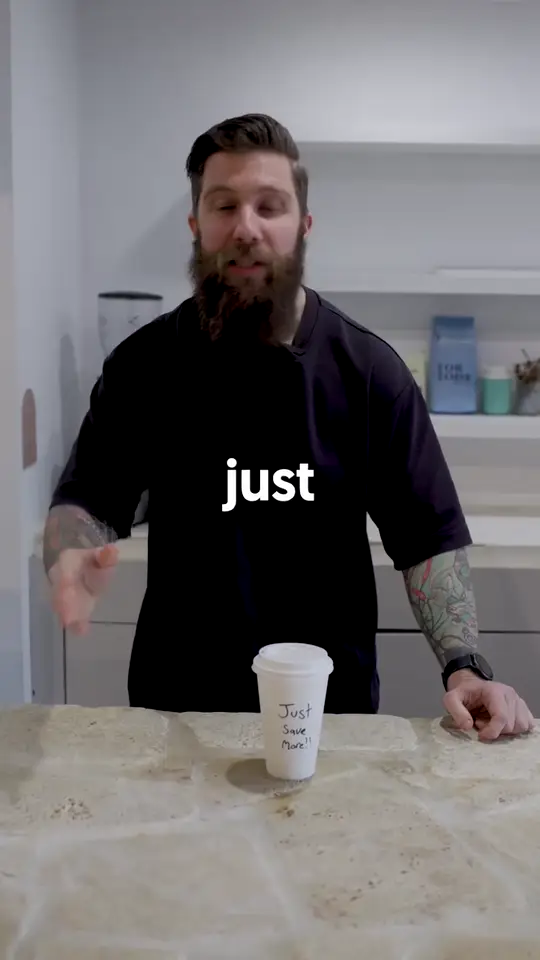 The Bearded Broker talking to camera in a kitchen with a takeaway coffee cup.